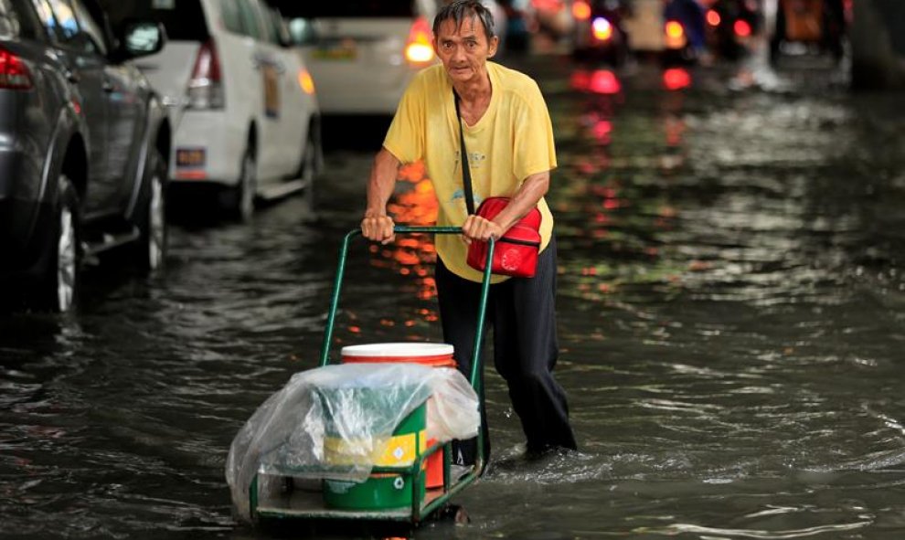 Un ciudadano filipino empuja un carro por una carretera inundada que lleva al aeropuerto en Parañaque, Filipinas. EFE/Eugenio Loreto