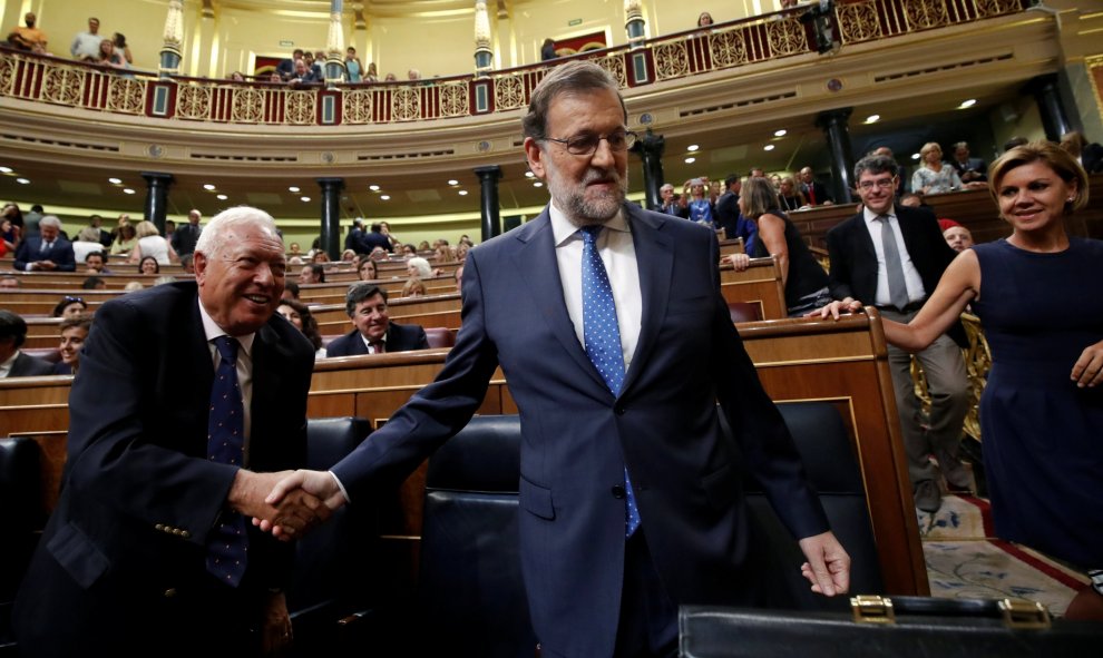 El presidente el Gobierno en funciones, Mariano Rajoy, se da un apretón de manos con Garcia-Margallo antes del debate de investidura en el Congreso de los Diputados. REUTERS/Juan Medina