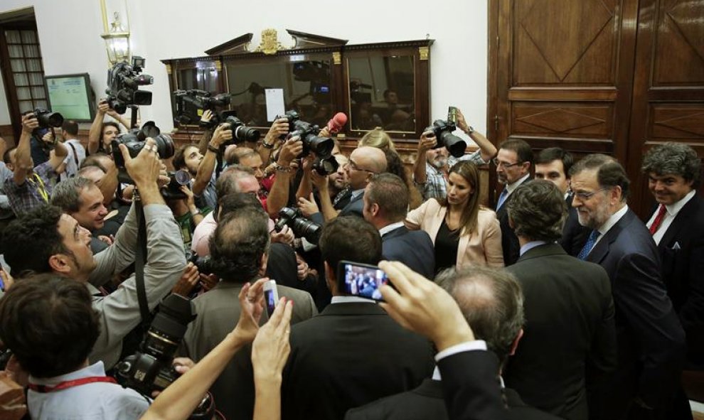 El presidente del Gobierno en funciones, Mariano Rajoy (2d), ante los medios gráficos en el pasillo del Congreso de los Diputados, tras abandonar el hemiciclo después de pronunciar esta tarde su discurso de investidura. EFE/Emilio Naranjo