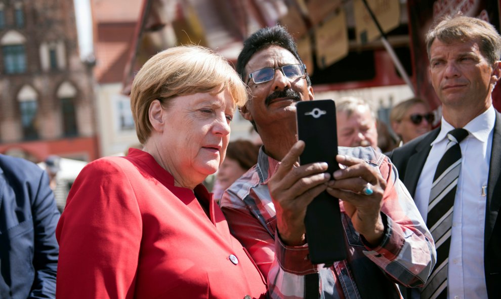 La canciller alemana Angela Merkel se hace un selfie durante su visita a un mercado de Greifswald, Alemania. REUTERS / Stefanie Loos