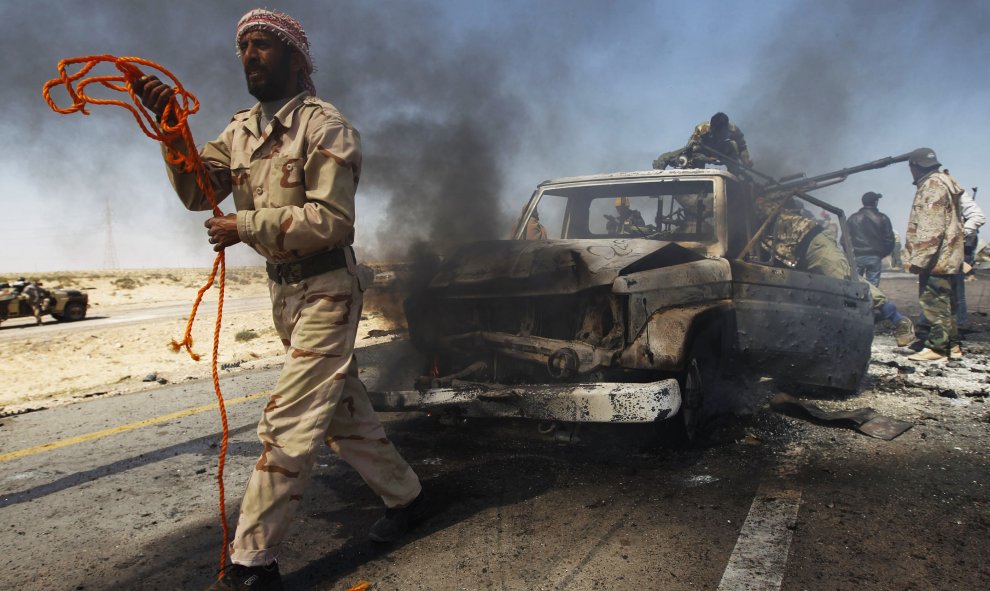 Un combatiente rebelde se prepara para remolcar un vehículo del gobierno después de ser golpeado por un ataque aéreo de la OTAN en las afueras de Brega. REUTERS/Andrew Winning