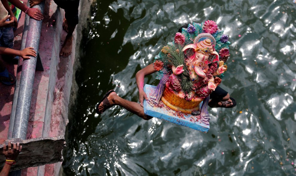 Un devoto que lleva un ídolo del dios hindú Ganesh, el dios de la prosperidad, salta al río Sabarmati para sumergir el ídolo en el último de los diez días de duración del festival de Ganesh Chaturthi en Ahmedabad, India. REUTERS/Amit Dave