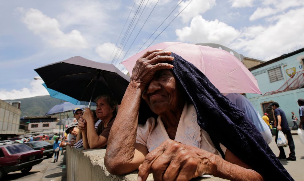 La gente se coloca en la línea, esperando para comprar artículos de primera necesidad y alimentos básicos en una acera cerca de un supermercado en Caracas, Venezuela. REUTERS/Henry Romero