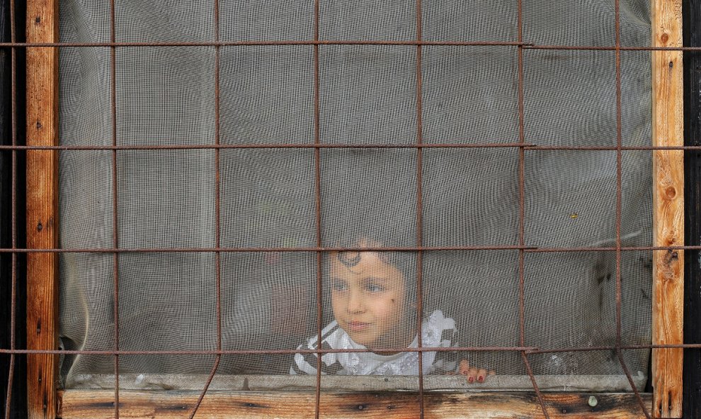 Un niño mira a través de una ventana dentro de un campo de refugiados y migrantes en el suburbio de Belgrado Krnjaca. REUTERS/Marko Djurica
