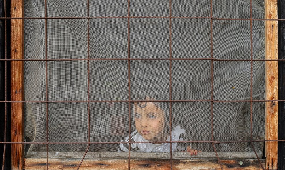 Un niño mira a través de una ventana dentro de un campo de refugiados y migrantes en el suburbio de Belgrado Krnjaca, Serbia. REUTERS / Marko Djurica