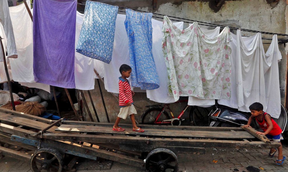 Unos niños juegan con un carromato en un suburbio de Mumbai en India. /REUTERS