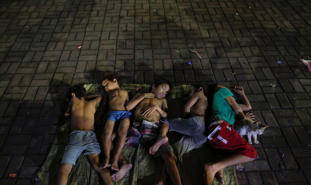 Niños duermen en medio de la carretera cerca de una iglesia de Manila. / REUTERS