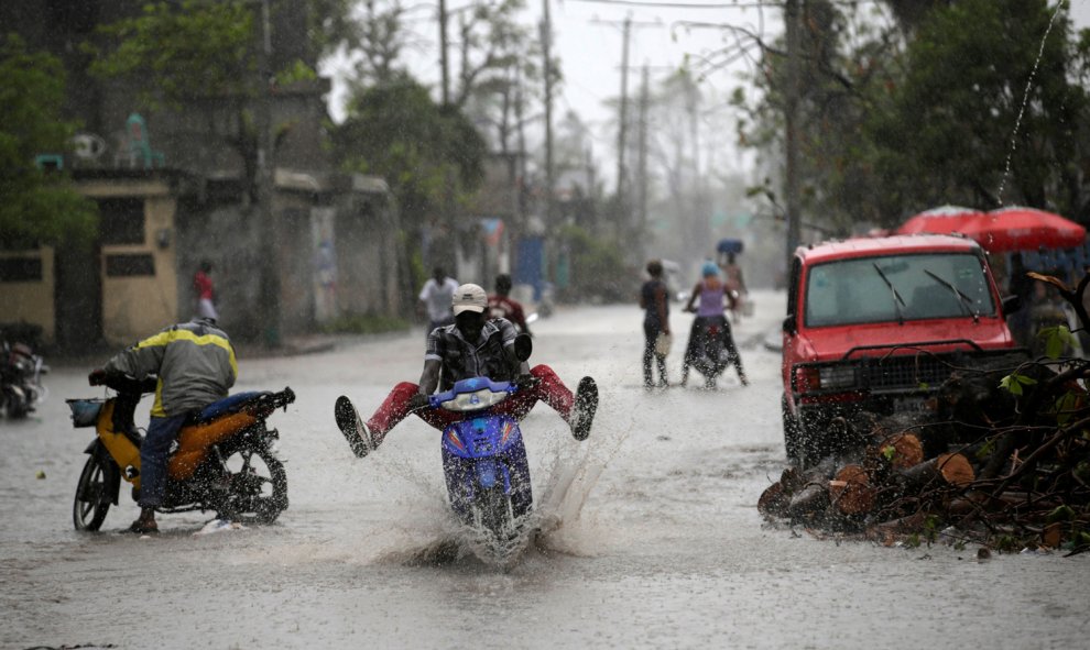 Un hombre conduce una moto sobre el suelo mojado por la lluvia tras el Huracán Matthew en Los Cayos, Haití. / REUTERS