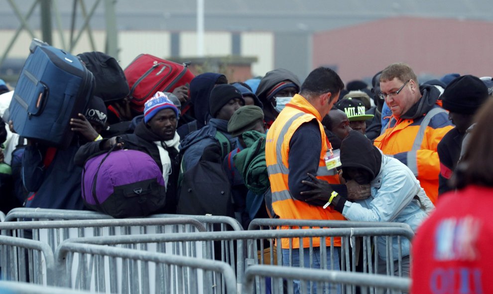 Refugiados hacen cola junto a las vallas antes de ser evacuados de la 'Jungla' de Calais. REUTERS