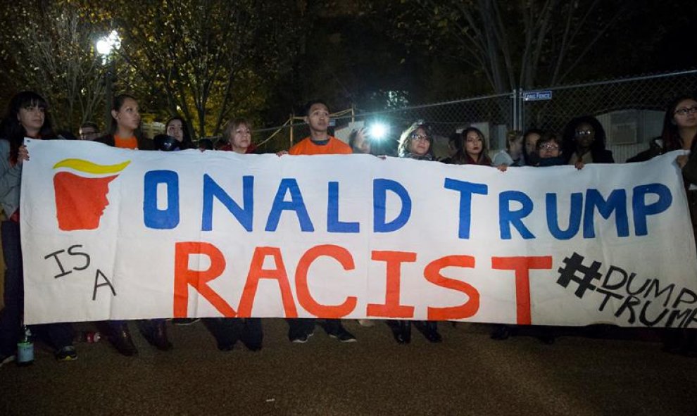 Unos inmigrantes sostienen una pancarta en la que se lee "Donald Trump es un racista" entre un grupo de personas reunidas frente a la Casa Blanca en Washington DC, Estados Unidos. EFE/Michael Reynolds