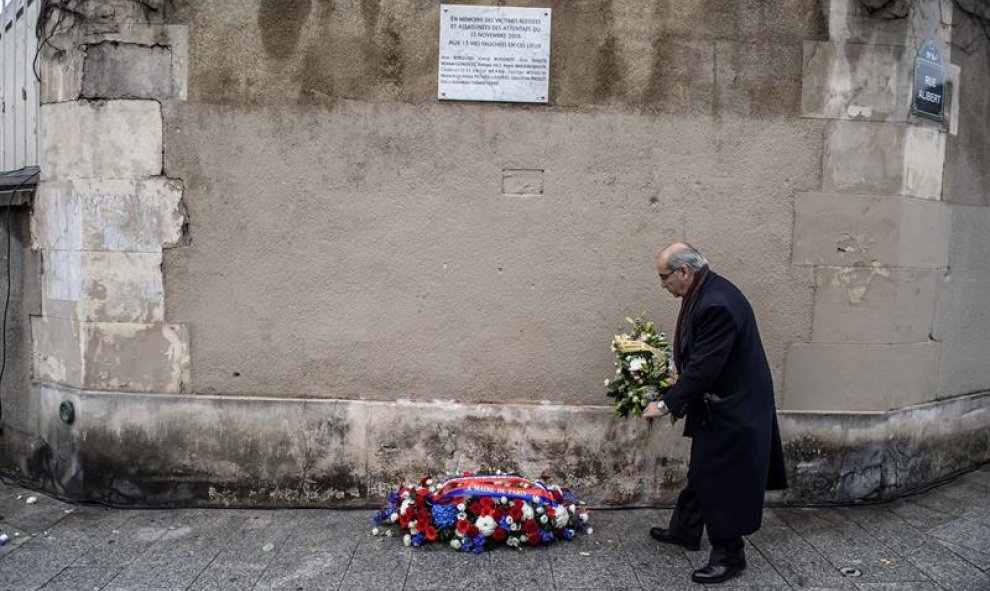 Un hombre deja un ramo de flores ante una placa conmemorativa de los atentados de hace un año./ EFE