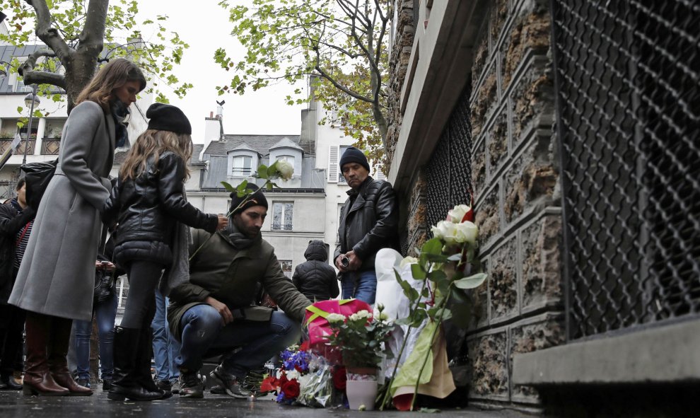 Varias personas dejan flores cerca del bar La Belle Equipe en París./ REUTERS