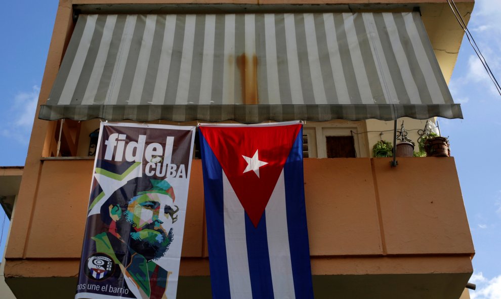Una bandera con la cara de Fidel Castro colgando del balcón de una casa, al lado de una bandera de Cuba en la Habana. / REUTERS