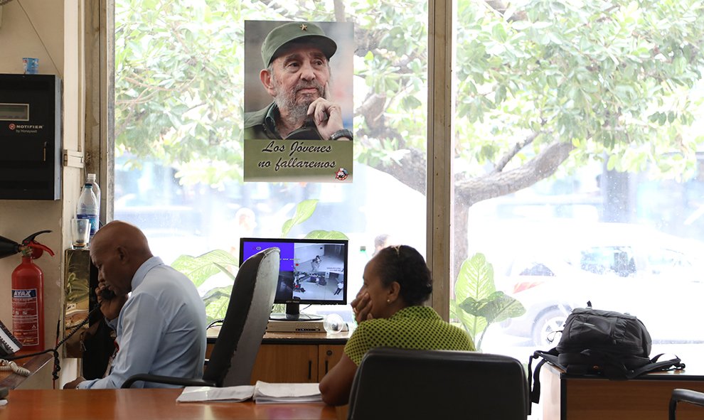 Trabajadores del centro internacional de prensa ante una fotografía de Fidel. /Marian León y Lucía M. Quiroga