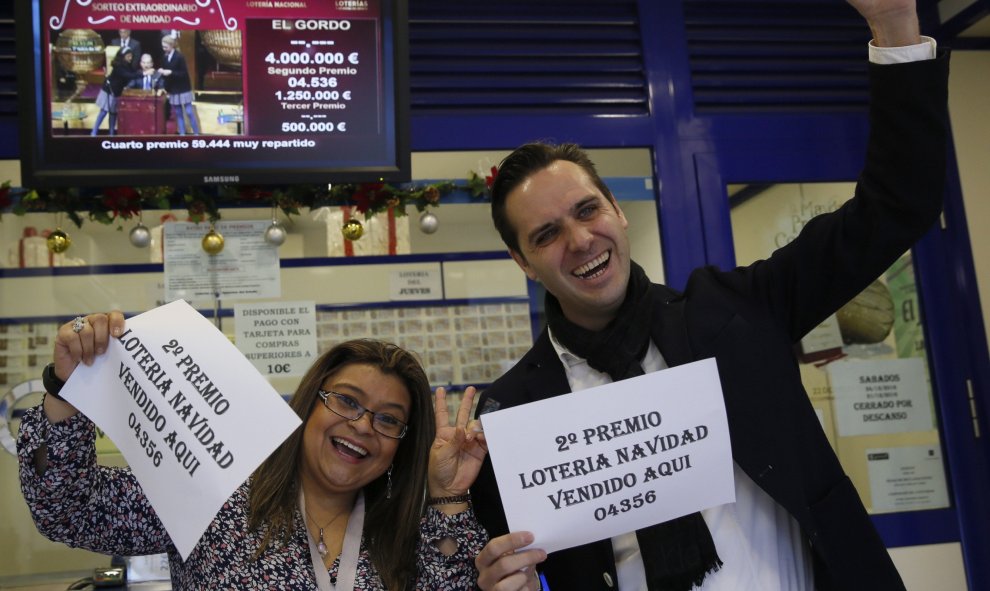 Marcos Delgado, dueño de la administración de lotería ubicada en la calle Condesa de Venadito en Madrid, acompañado de la vendedora Jenyffer Hoyos celebran su el segundo premio del Sorteo Extraordinario de la Lotería de Navidad que ha recaído en el 04536,