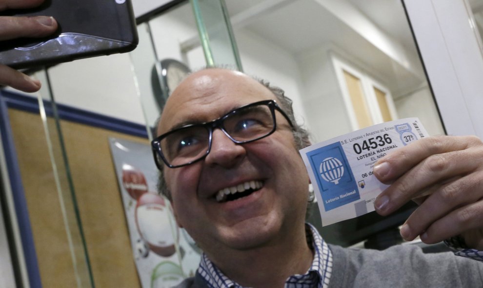 El administrador de lotería Óscar de Toro, se hace un selfie con el número agraciado con el segundo premio de la Lotería de Navidad, 4.536, vendido en su administración situada en un bar, esta mañana en Santiago de Compostela. EFE/lavandeira jr.