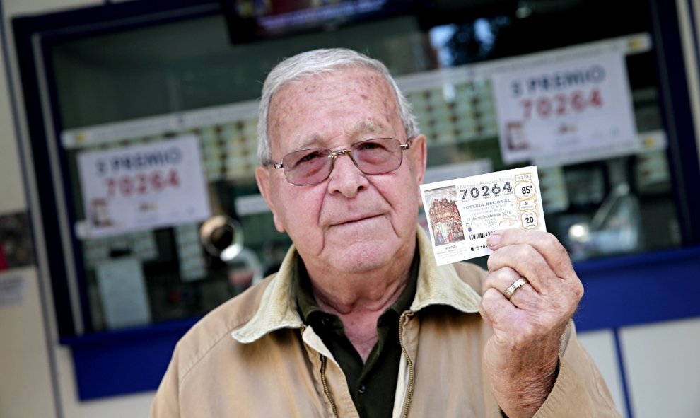 Un hombre posa hoy en Valencia con un décimo del número 70.624, que ha sido premiado con un quinto premio en el sorteo de Navidad, dotado con 60.000? a la serie. EFE/Manuel Bruque