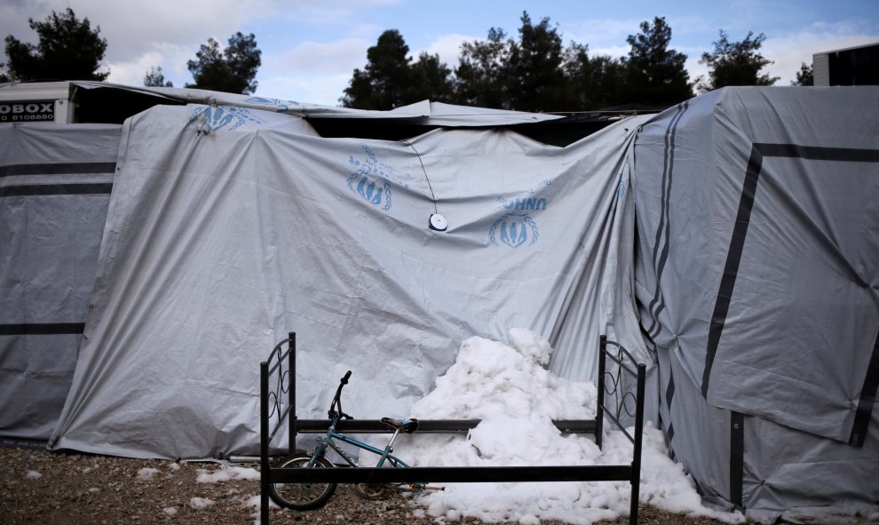 La nieve se amontona bajo una bicicleta y un somier viejo en el campo de refugiados de Ritsona, en Atenas. REUTERS/Alkis Konstantinidis