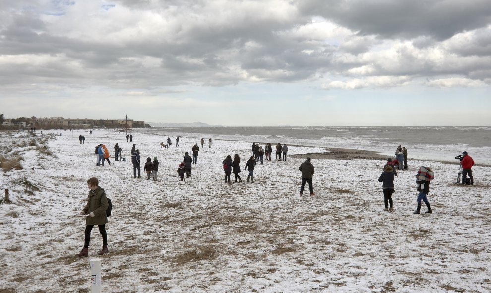 Decenas de curiosos pasean por una de las playas de Dénia que ha amanecido hoy cubierta de nieve tras el temporal que afecta a la zona. /EFE
