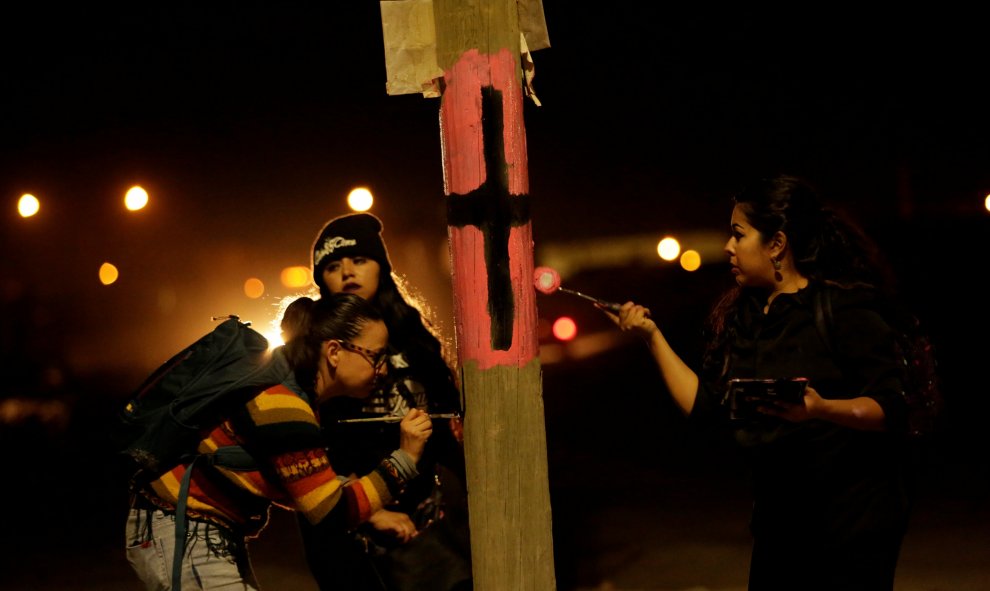 Unas activistas pintan una cruz negra en una farola para recordar a las víctimas de violencia machista con motivo del Día Internacional de la Mujer en Ciudad Juárez, Mexico. REUTERS/Jose Luis Gonzalez