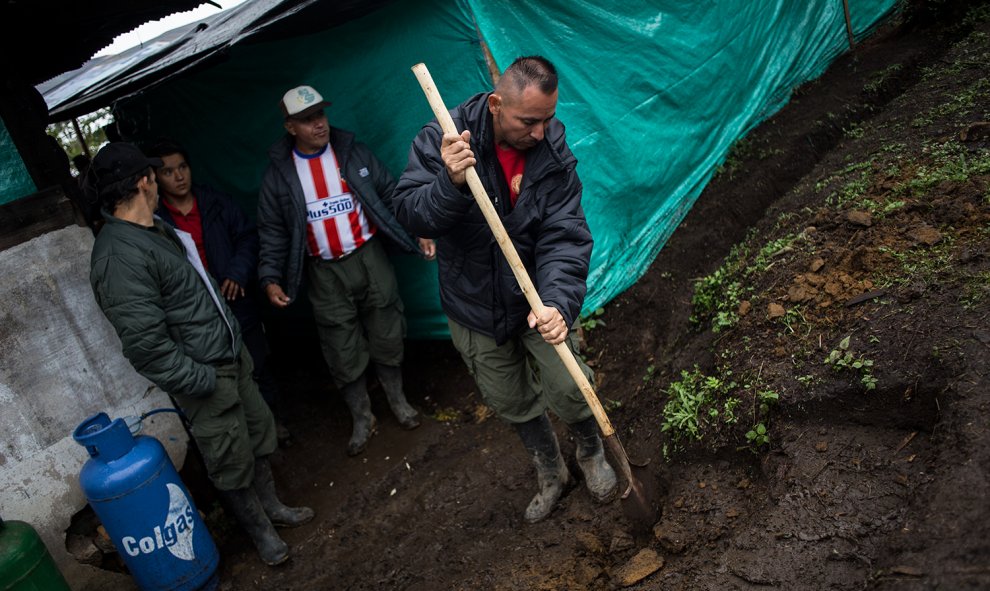 Varios guerrilleros de las FARC retiran el barro producido por la lluvia en el campamento de transición para la guerrilla en La Fila, en la región de Tolima, Colombia.- JAIRO VARGAS