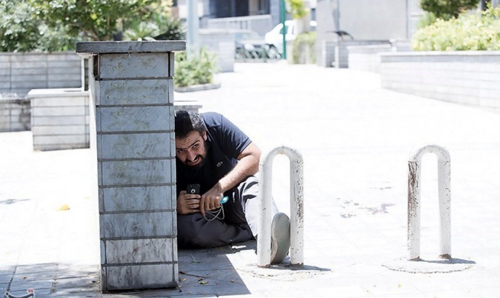 Un hombre se cobija durante el ataque al Parlamento de Irán en el centro de Teherán. / REUTERS
