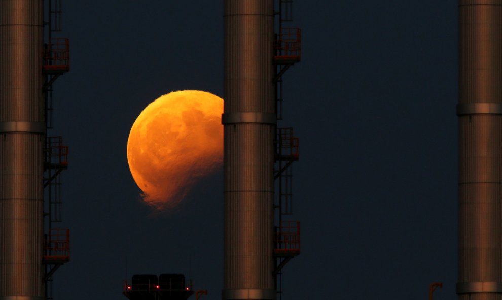 Imagen del eclipse lunar detrás de las chimeneas de una central eléctrica en Delimara (Malta). Darrin Zammit / REUTERS