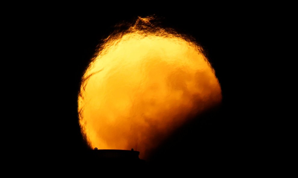 Imagen del eclipse lunar detrás de las chimeneas de una central eléctrica en Delimara (Malta). Darrin Zammit / REUTERS