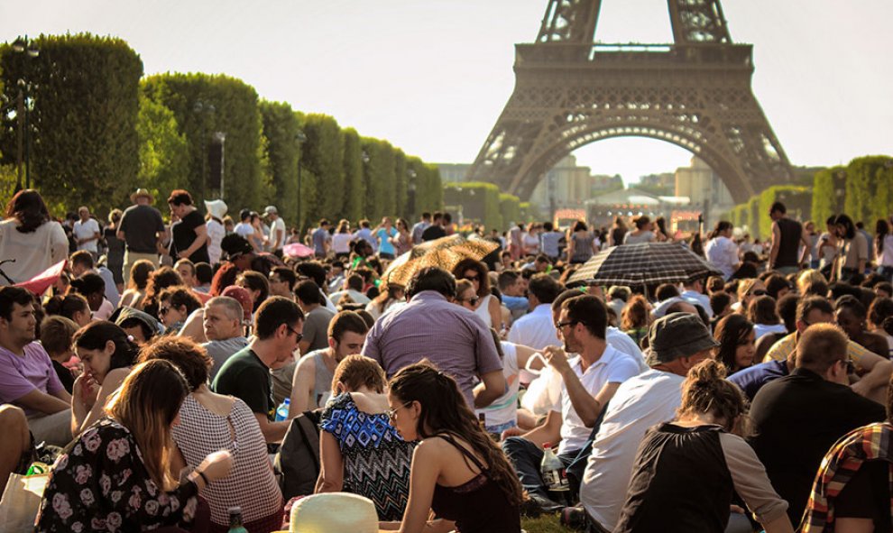 Numerosos grupos de turistas hacen un picnic frente a la Torre Eiffel /Architecture and Design