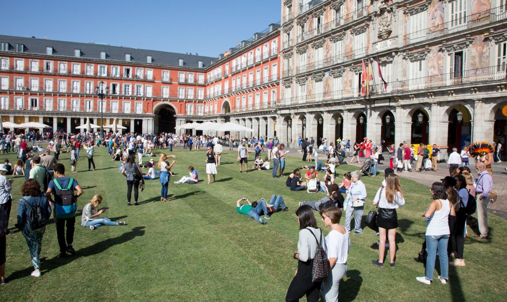 La gente toma el sol sobre el césped en la Plaza Mayor.- CHRISTIAN GONZÁLEZ