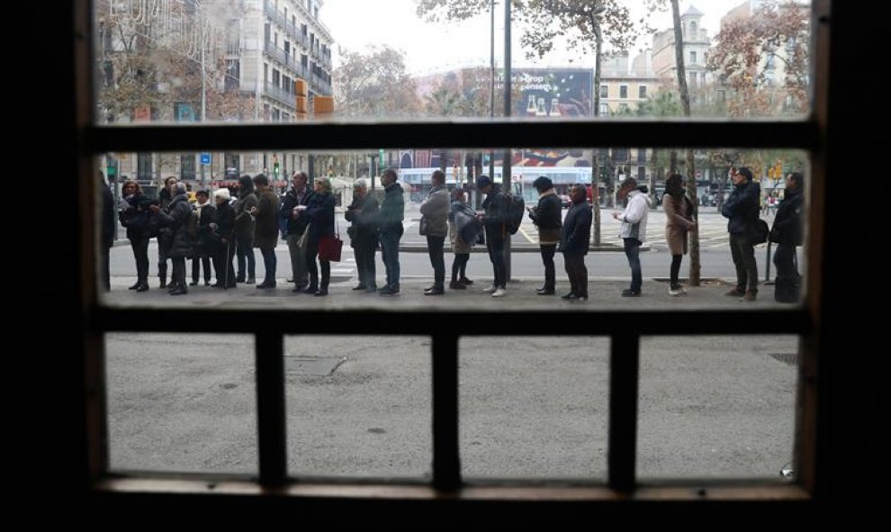 Numerosos ciudadanos guardan cola en el colegio electoral de la Plaza de la Universidad de la ciudad condal. / EFE