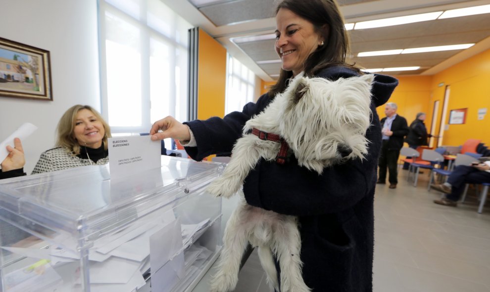 Una mujer, con su perro en brazos, desposita su voto en un colegio electoral de Barcelona. REUTERS/Eric Gaillard