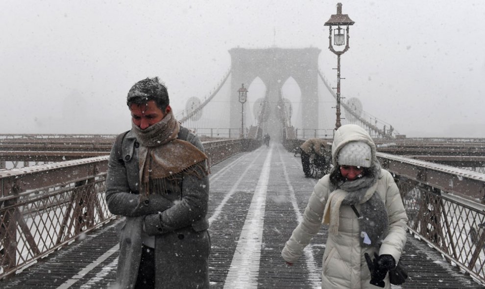 Varias personas caminan por el puente de Brooklyn, en Nueva York, en medio de la peor tormenta de la temporada en EEUU, que ha afectado a todo el noroeste del país.	REUTERS/Darren Ornitz
