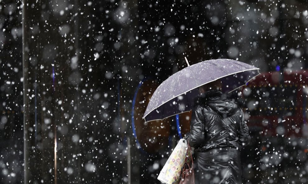 Una mujer camina bajo la nieve en Pamplona. EFE