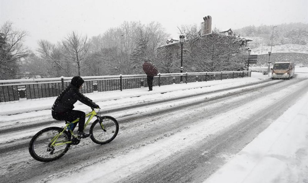 Un ciclista intenta acceder a la PA-30 en Huarte tras la intensa nevada que ha caído esta madrugada en la capital navarra. / EFE