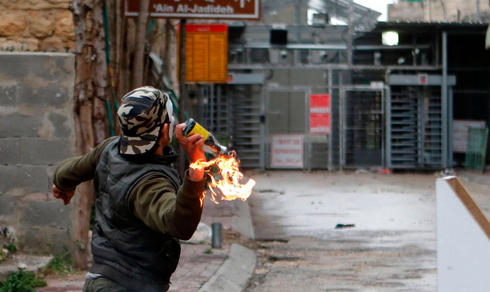 Un palestino lanza un cóctel molotov contra soldados israelíes durante enfrentamientos en Hebrón, Palestina, durante las protestas con motivo del Día de la Tierra. Los palestinos recuerdan la muerte de seis árabes israelíes en Galilea, en el norte de Isra