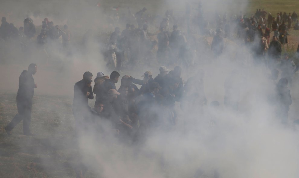 Los palestinos huyen del gas lacrimógeno disparado por las tropas israelíes durante los enfrentamientos, durante una protesta a lo largo de la frontera de Israel con Gaza, exigiendo el derecho a regresar a su tierra natal, al este de la ciudad de Gaza.- R
