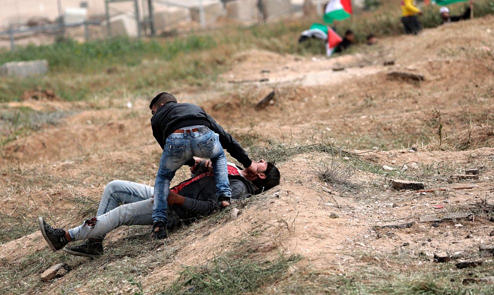 Un palestino ayuda a un compañero herido durante los enfrentamientos con soldados israelíes en el este de Beit Hanun, norte de la Franja de Gaza.-  EFE/Mohammed Saber