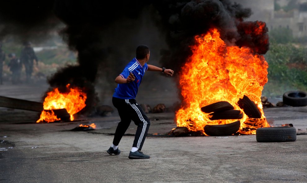 Un palestino lanza una piedra durante los enfrentamientos con soldados israelíes en la ciudad cisjordana de Ramala.-EFE/Alaa Badarneh