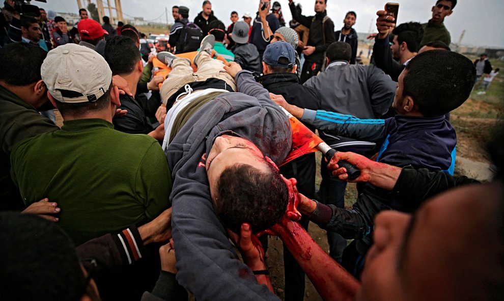 Varios palestinos trasladan a un compañeros fallecido de un disparo en la cabeza durante los enfrentamientos con soldados israelíes en el este de Beit Hanun.- EFE/Mohammed Saber