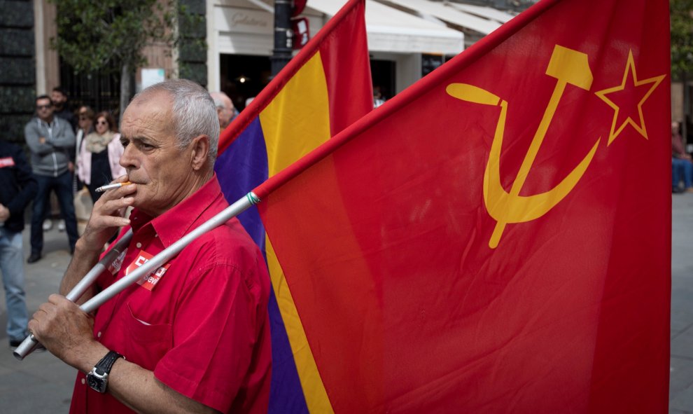 Un veterano manifestante con las banderas republicana y del Partido Comunista espera fumando la salida de la manifestación del Primero de Mayo en Sevilla , donde miles de personas se han dado cita para reivindicar la igualdad de género, el empleo de cali