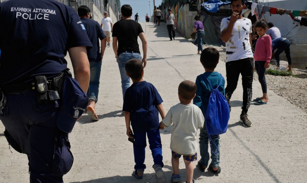 Tres niños pequeños solos de la mano recorren el campamento entre adultos desconocidos y policías. / M.I