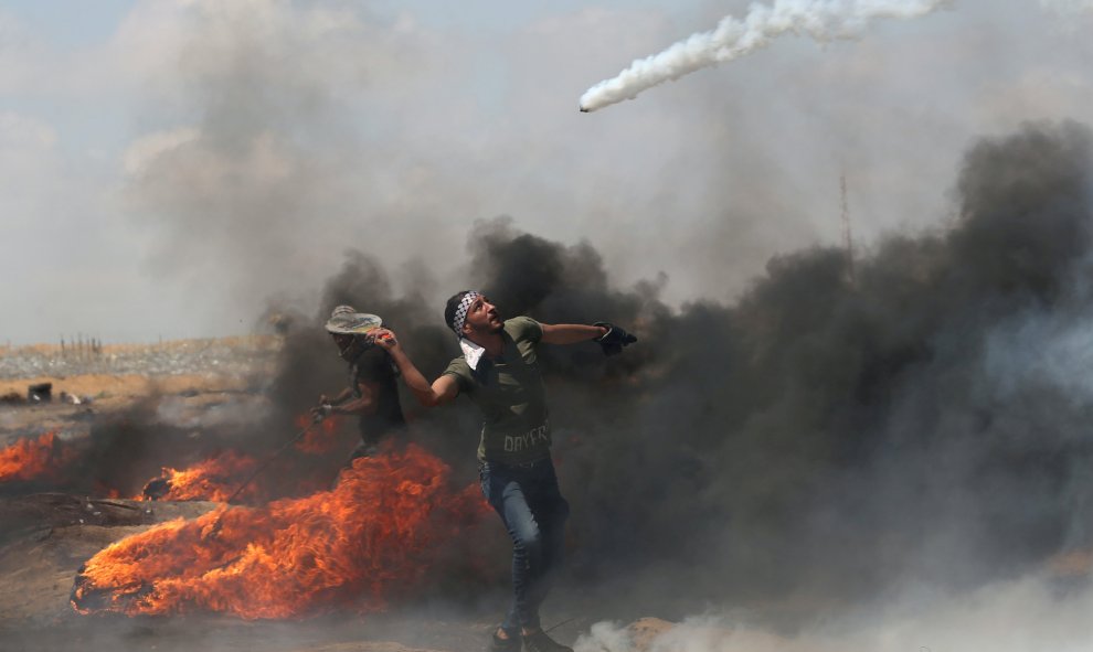 Un joven con una raqueta en la mano para alcanzar un bote de gas lacrimógeno en Gaza/Reuters