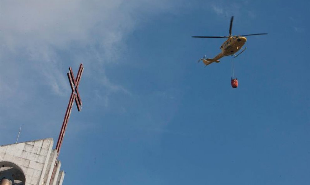 Un helicóptero que transporta agua se acerca hasta las inmediaciones del almacén pirotécnico/EFE