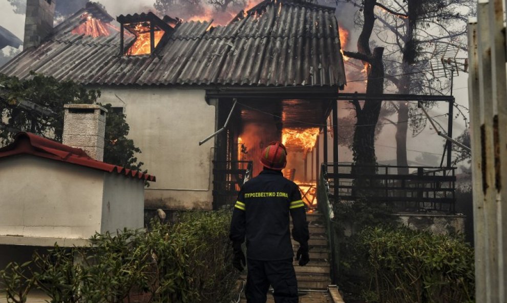 Un bombero frente a una casa en llamas en el incendio de Kineta, cerca de Atenas - AFP