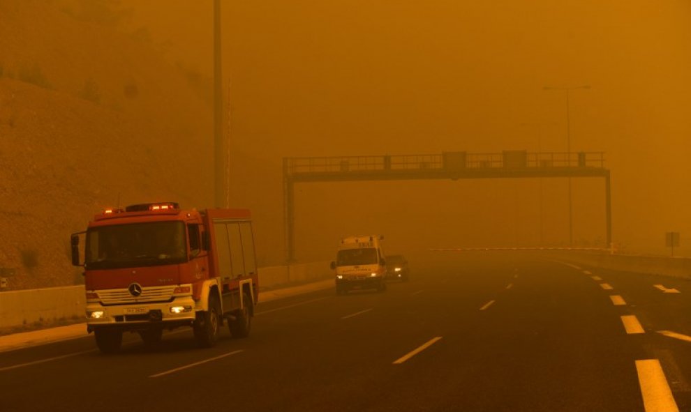 Un coche de bomberos se observa entre el humo del incendio en Kineta, cerca de Atenas - AFP