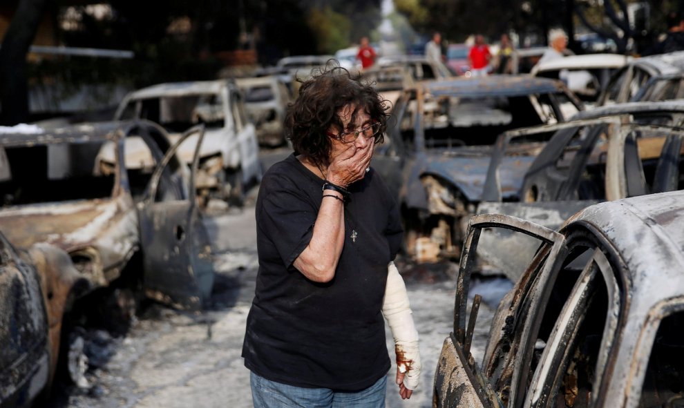 Una mujer busca a su perro después del incendio en el pueblo de Mati. REUTERS/Costas Baltas
