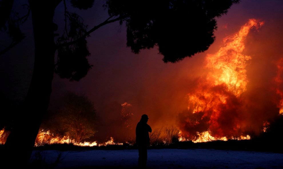 Un hombre observa las llamas del incendio en la ciudad de Rafina. REUTERS/Costas Baltas