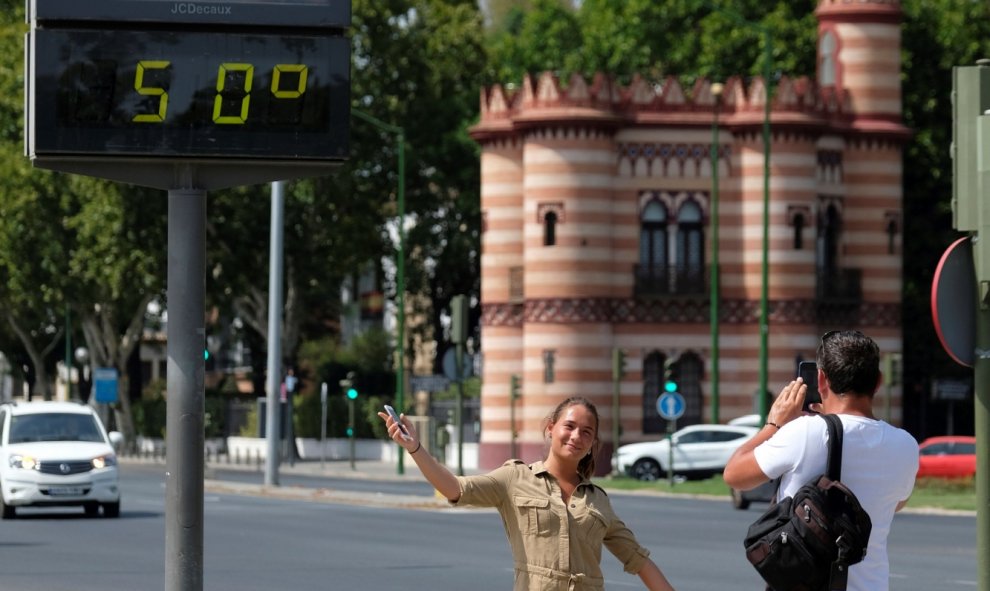 Una turista se fotografía bajo un termómetro que marca 50ºC hoy en Sevilla. EFE/Pepo Herrera