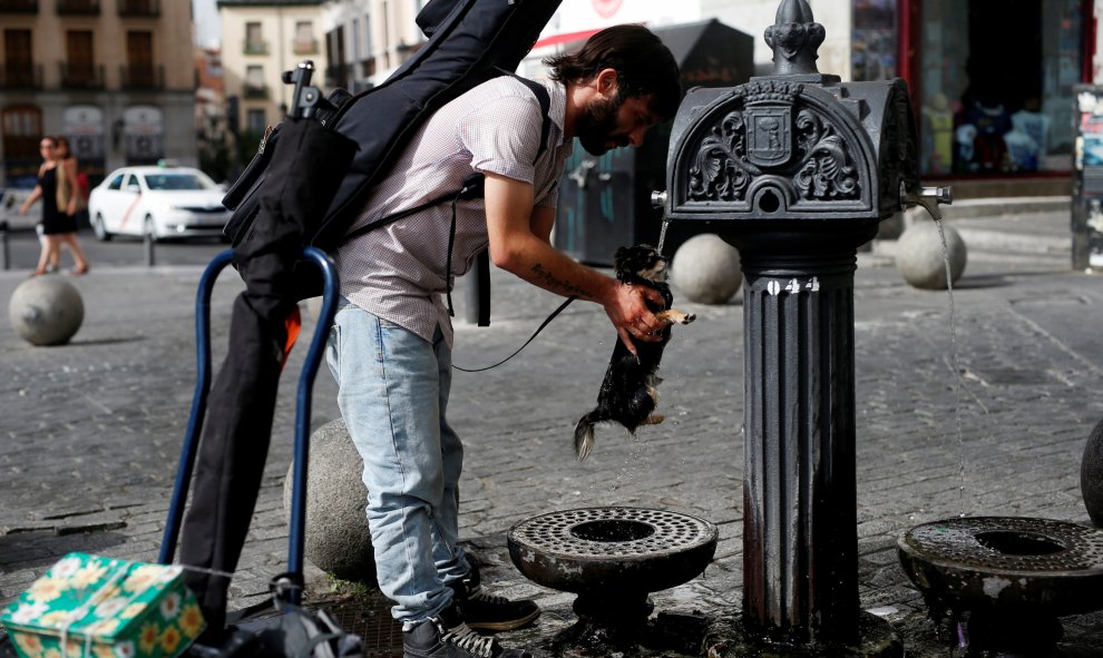 Un hombre refresca a su perro en una fuente pública de Madrid. REUTERS/Javier Barbancho